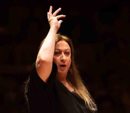 Simone Young conducts with one hand raised.