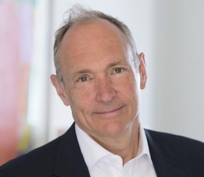 Man in a suit with a kind smile, standing indoors.