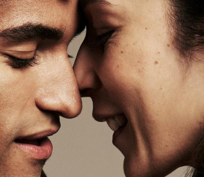 Two dancers with their faces close to touching, eyes closed.