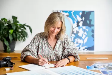 A seated woman sketching in a notebook.