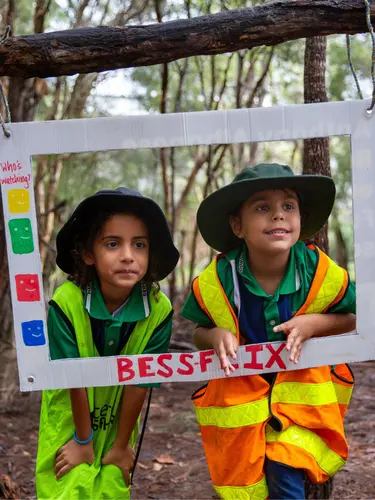 Two students posing behind a paper frame that reads "BessFlix"