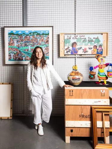 Coby Edgar a curator standing next to Badu Gili artwork.