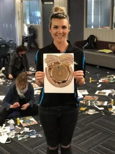 A blonde woman holding a painting.