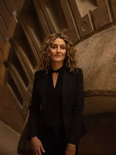 A woman with blonde curly hairs in a black dress.