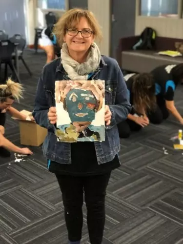 An old woman holding a painting.