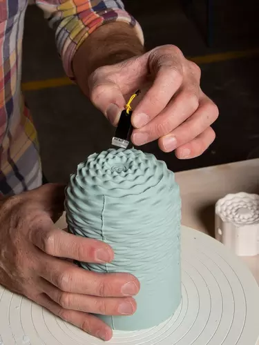 Hands crafting a blue object.