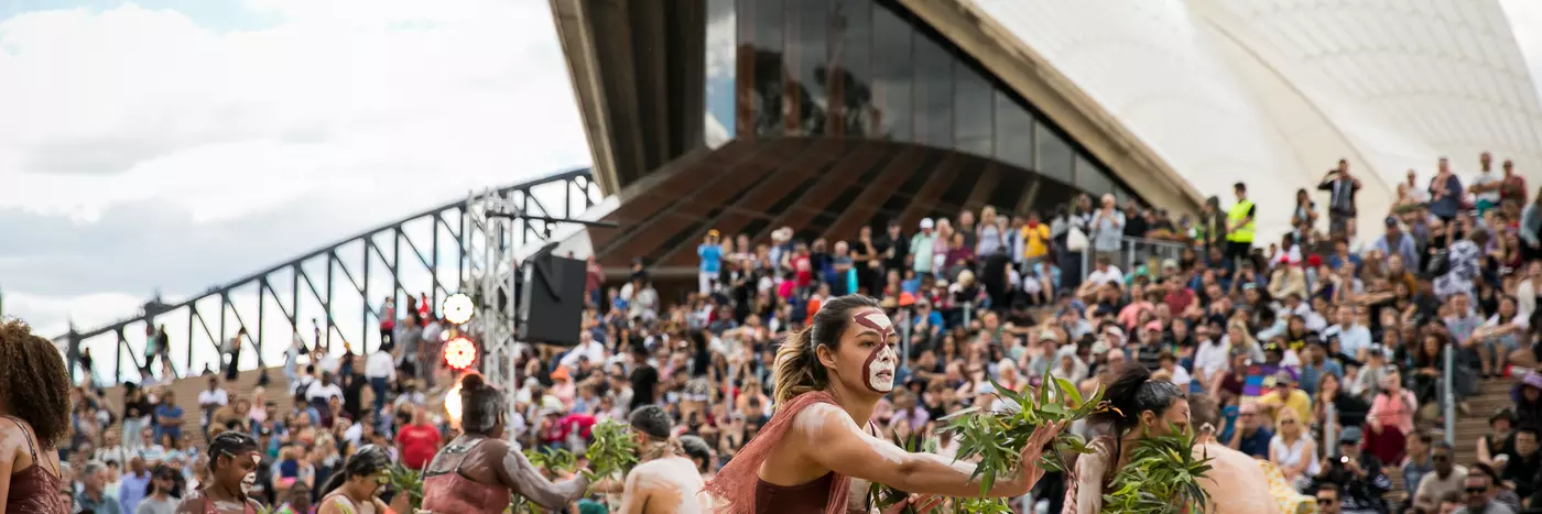 Women in sand pit performing indigenous dance in the Homeground of Sydney opera house.