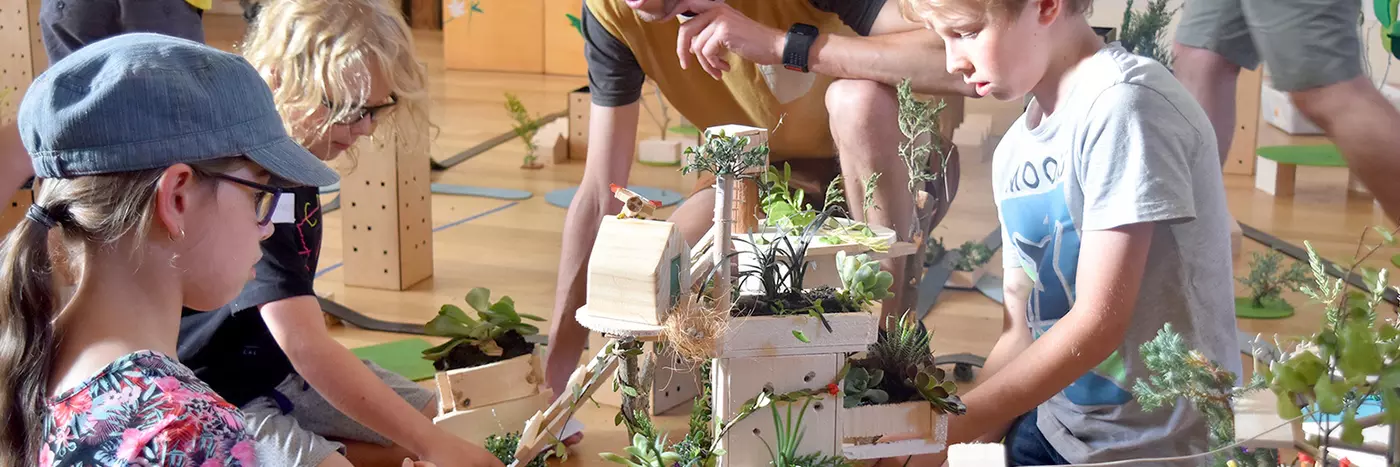 A man helping kids build a house model.