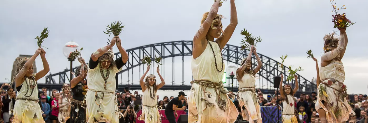 Women in sand pit performing indigenous dance in the Homeground of Sydney opera house.