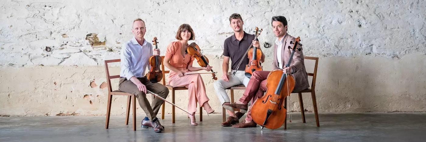 A string quartet holds their instruments looking at the camera