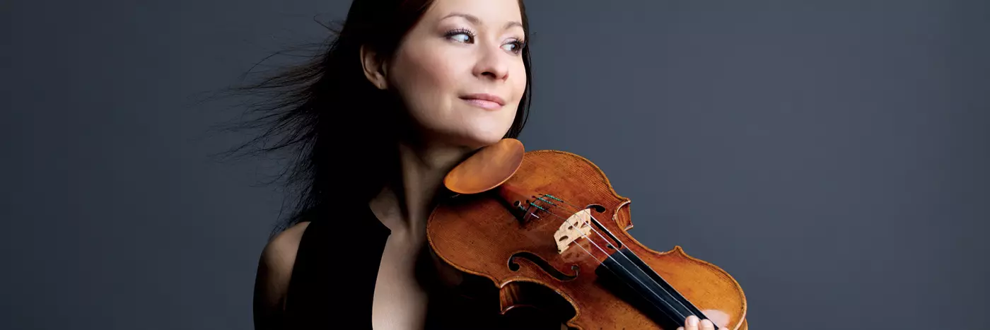 A woman with brown hairs holding a violin.