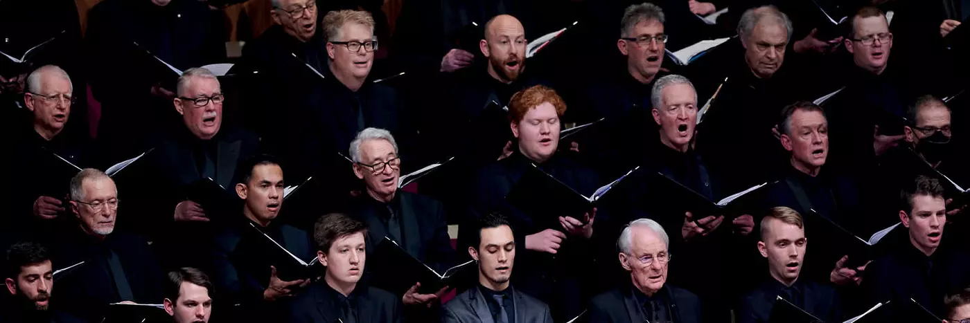 A choir singing with black folders in their hands.