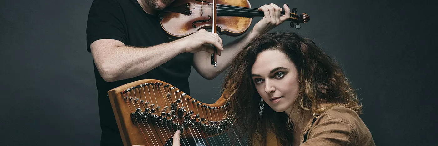 A man playing a violin and a woman playing a harp.