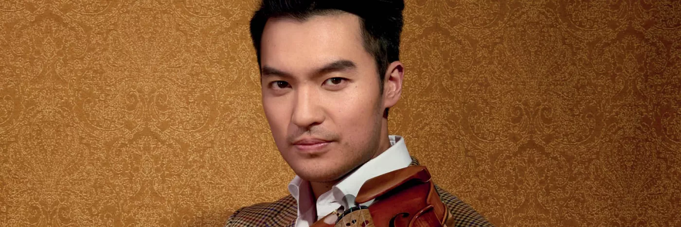 A man a brown suit holding a violin.