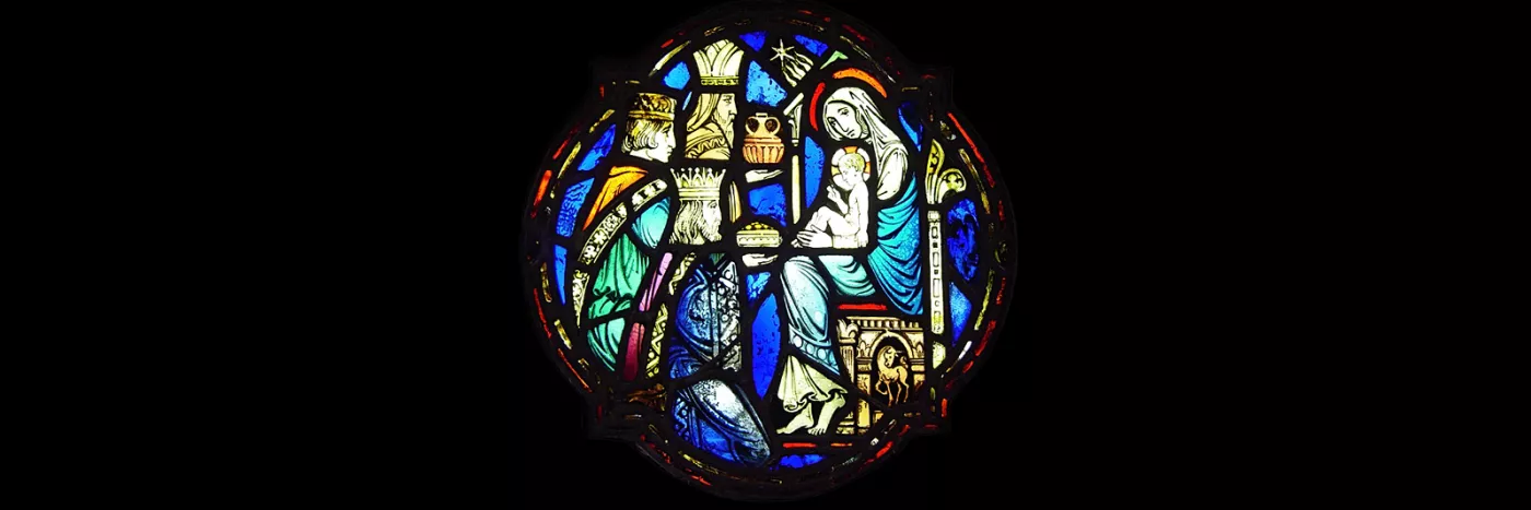 A medieval glass stained window of three kings bringing gifts to the Mother Mary and Jesus