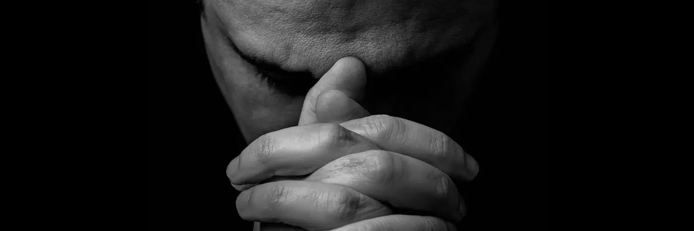 A man resting his forehead on his hands.