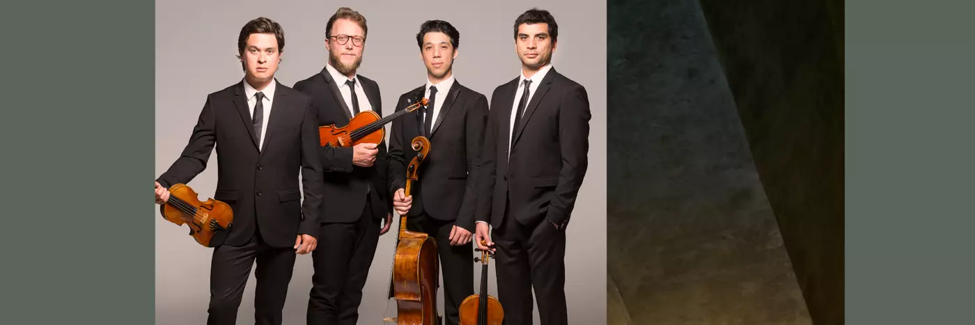 Four men in black suit holding violins and a cello.