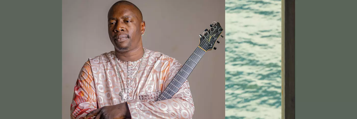 Vieux Quartet Toure a Malian singer in traditional wear holding his guitar.