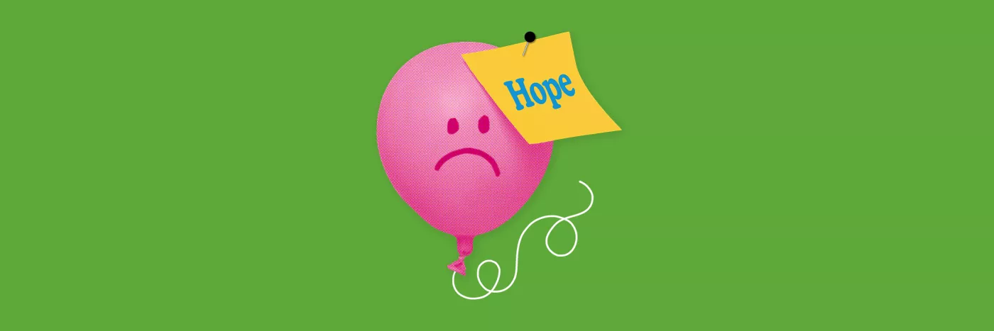 A pink balloon with a sad face on it has a post it note saying 'hope' pinned into it.