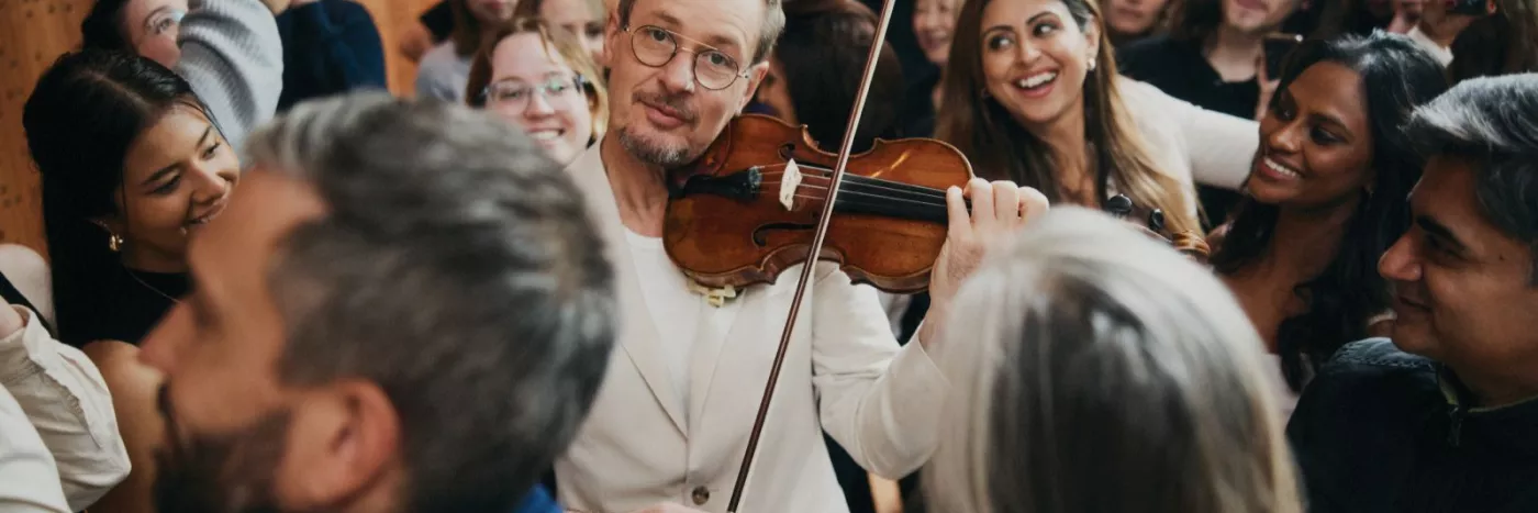 A man plays violin while the crowd encircles him.