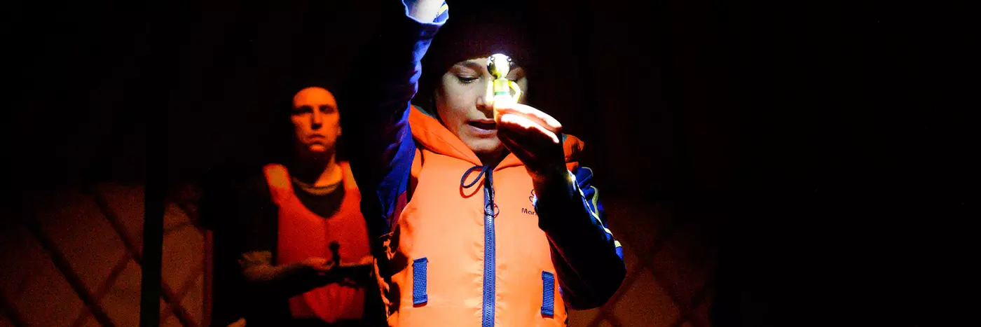 A person wearing a lifejacket and holding a torch.