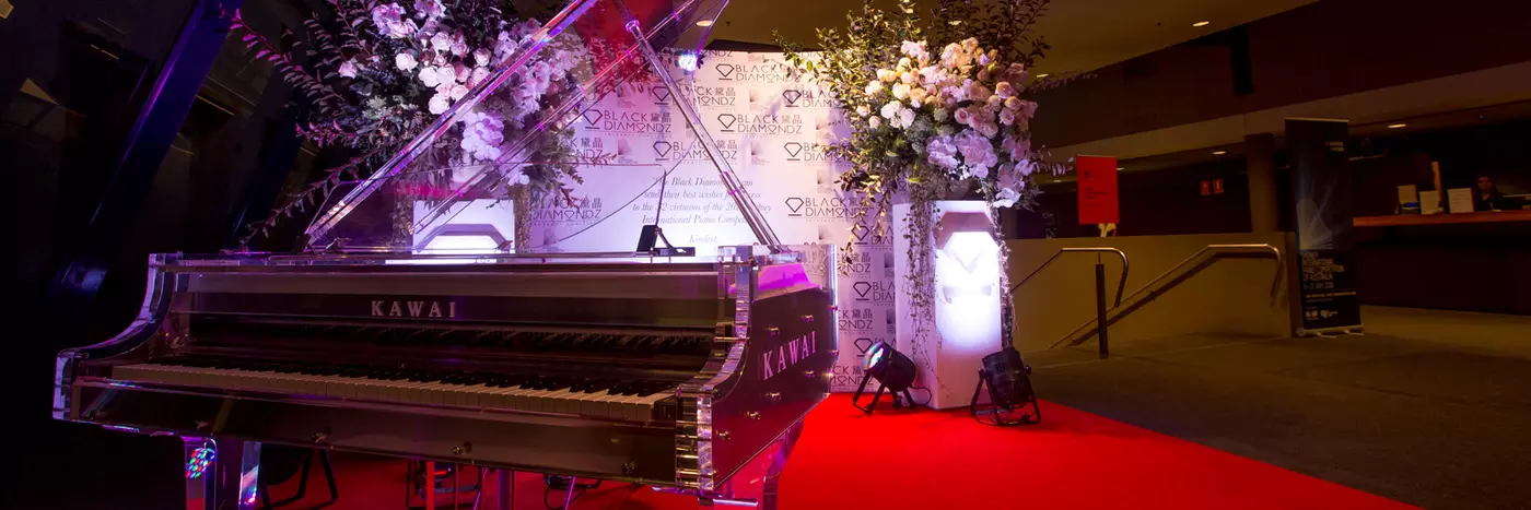 A fancy grand piano with flowers around it.