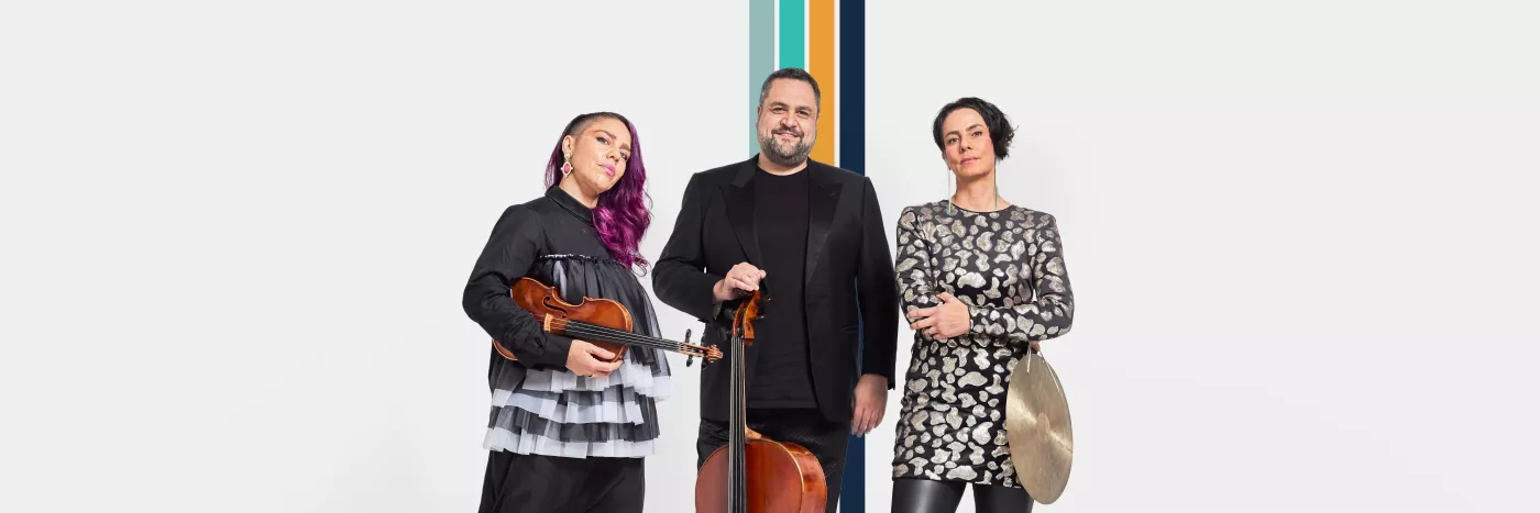 Two women and one man pose for a picture holding a violin, cello and cymbol.