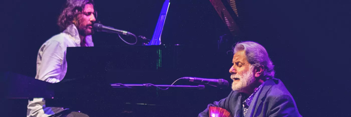 Two men playing grand piano and a guitar.