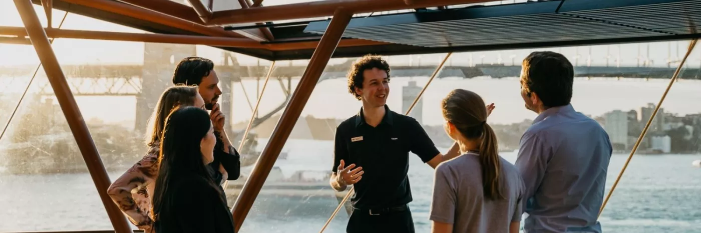 A tour guide with a group of people outside the Sydney opera house.