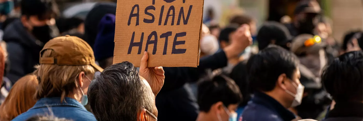 A crowd of people in masks with a sign titled 'Stop Asian Hate'.