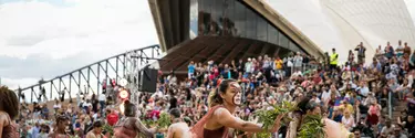 Women in sand pit performing indigenous dance in the Homeground of Sydney opera house.