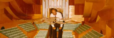 A man stooping under the organ of a large scale model of the Concert Hall, looking at the perspex discs.