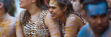 Women with aboriginal face makeup sitting in the sand pit at Homeground.