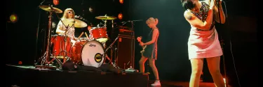 Bikini Kill a rock band performing on the stage.