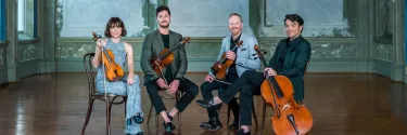 A group of string ensemble sitting on the chair.