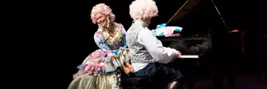A man and woman dressed up as Mozart and his wife in colourful outfits and big white wigs