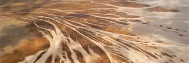 A very wide bird's eye view of empty brown arid land with river systems zip zagging through the land