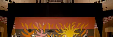 A team of men and women installing the tapestry curtain in the Concert hall.