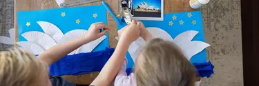 Kids creating sails of the Sydney opera house by cutting paper plates.