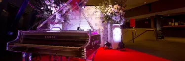 A fancy grand piano with flowers around it.