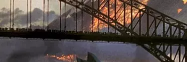 The Harbor bridge and Sydney Opera House in front of a large object on fire.