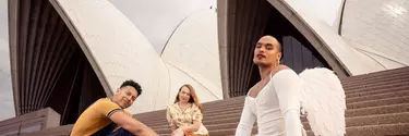 Three individuals sitting outside on the stairs of Sydney opera house.