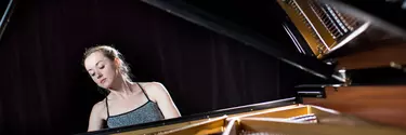 A blonde woman playing a grand piano.