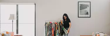 A woman looking through a railing of materials hanging from coat hangers.