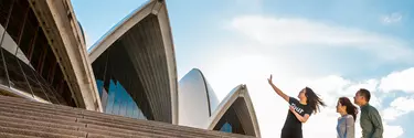 A tour guide outside Sydney opera house with a couple.