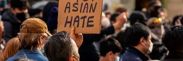 A crowd of people in masks with a sign titled 'Stop Asian Hate'.