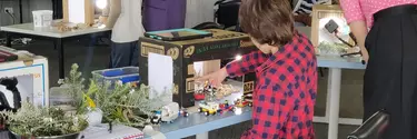 A young boy moving toy cars within a cardboard box