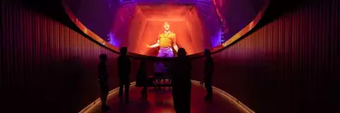 A group of visitors watching a projection of an event on ceiling screens.