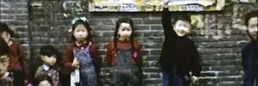 Children lined up against a brick wall.