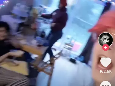 A screenshot of a TikTok of a person with pink hair shouting.